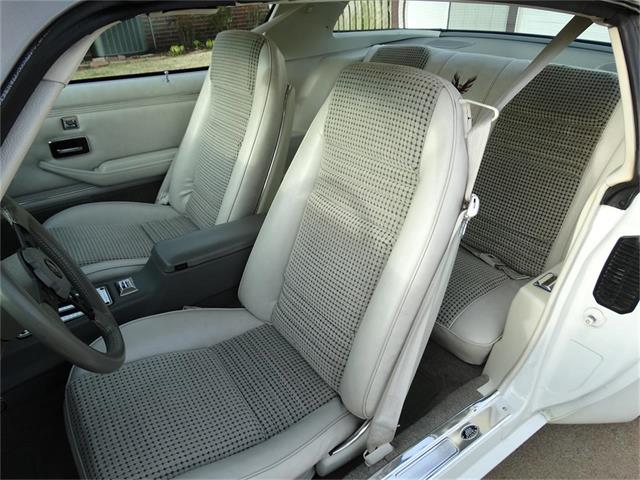White Trans Am Deluxe interior with light houndstooth cloth front bucket seats, viewed through the open driver's door