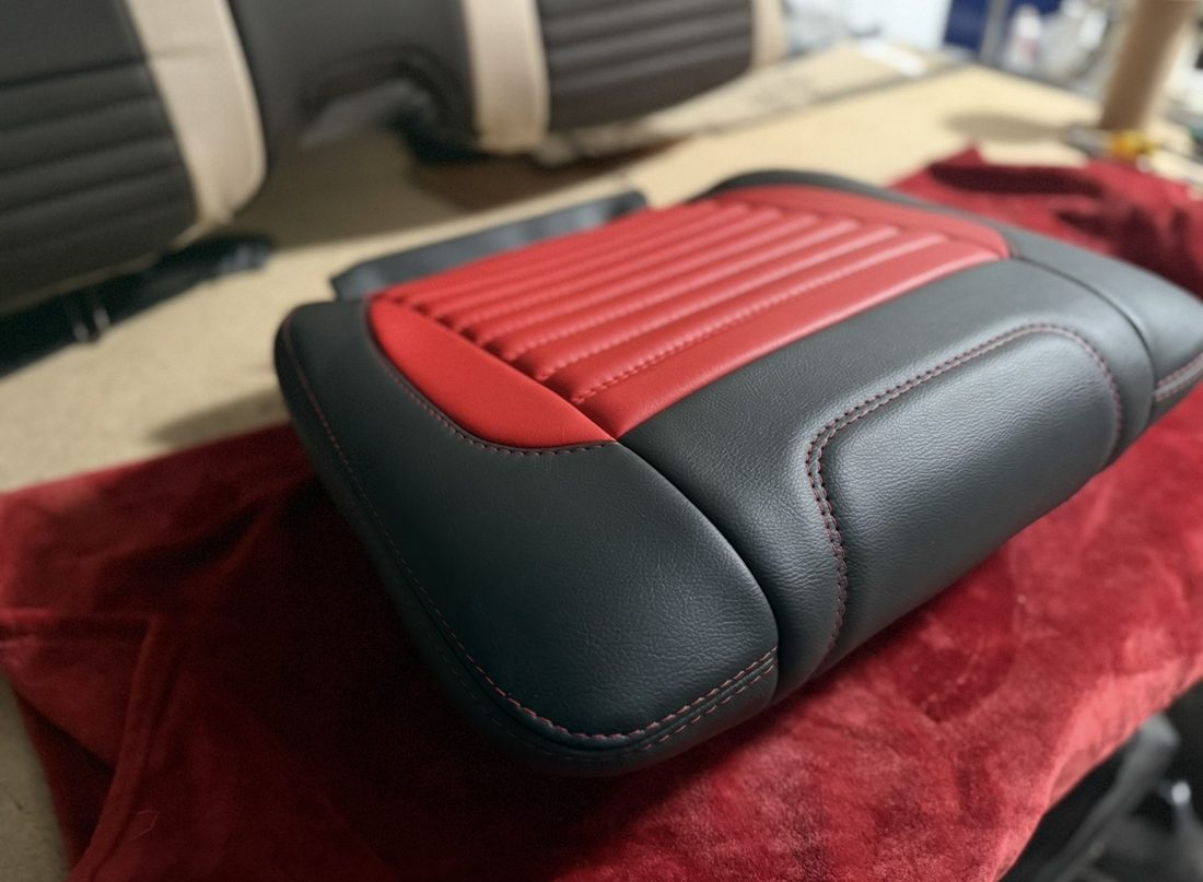 Close-up of clean French stitched seams on a red and black leather seat panel